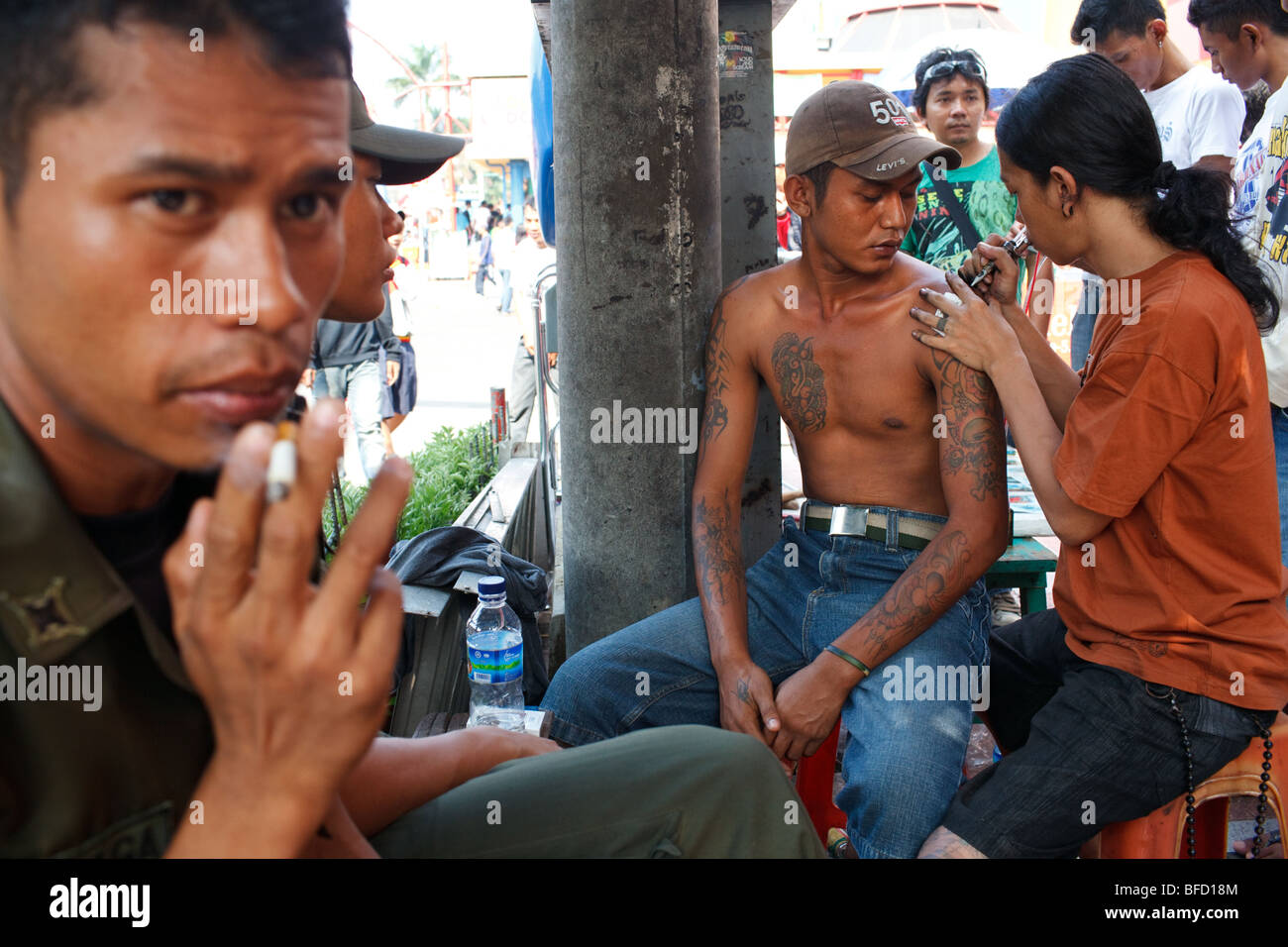 ein Künstler macht eine Tattoo für ein Mann auf der Straße in Blok M Bereich in Jakarta, Indonesien Stockfoto