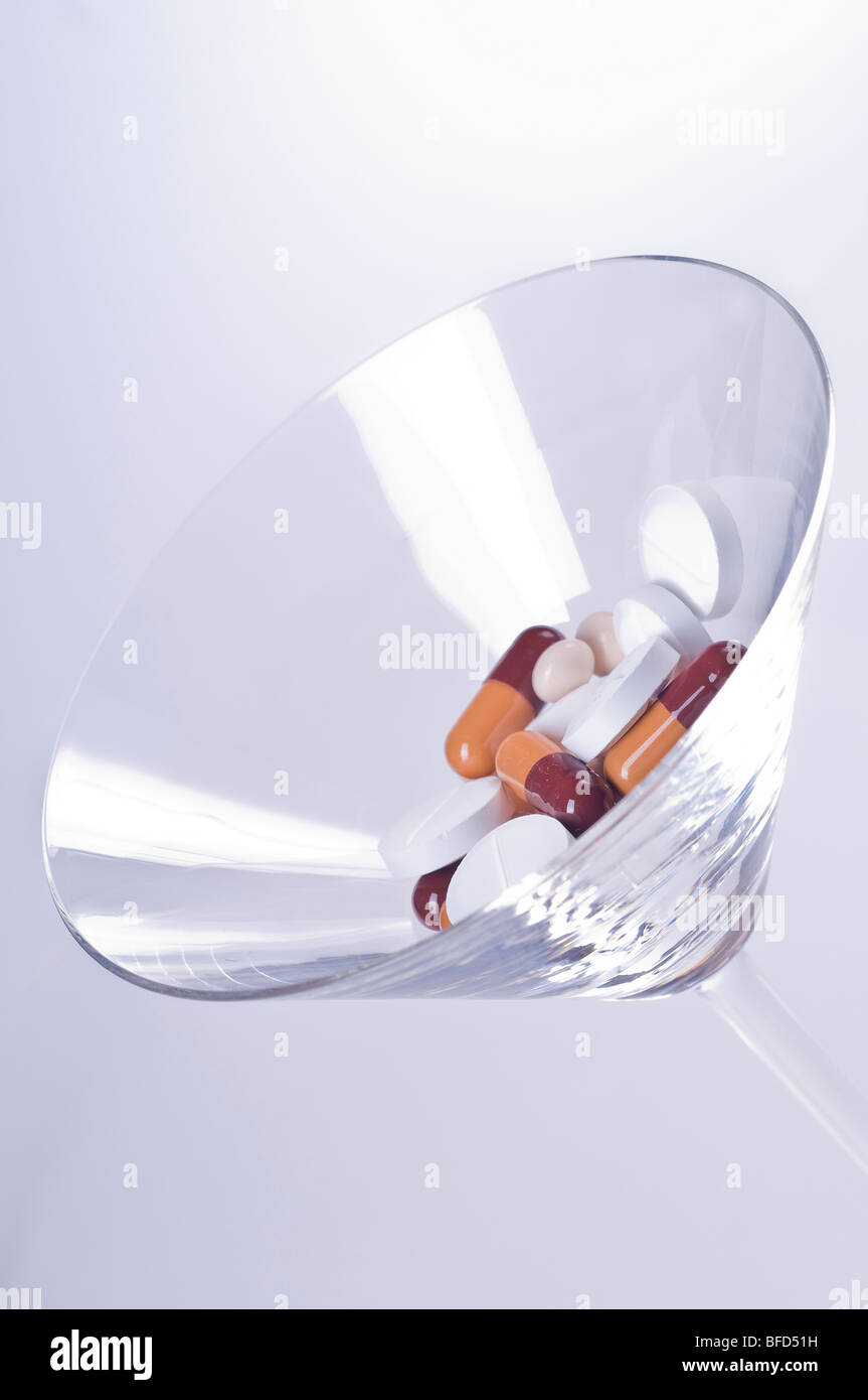 Verschiedene Pillen in ein Cocktailglas auf weißem Hintergrund Stockfoto