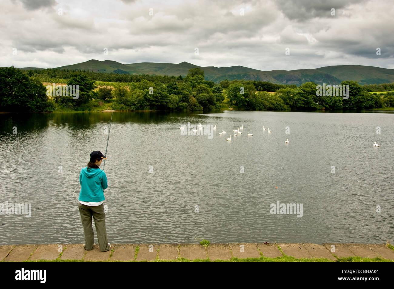 Frau, die am Ufer des Gartmorn-Staudamms in Schottland angeln soll. Stockfoto