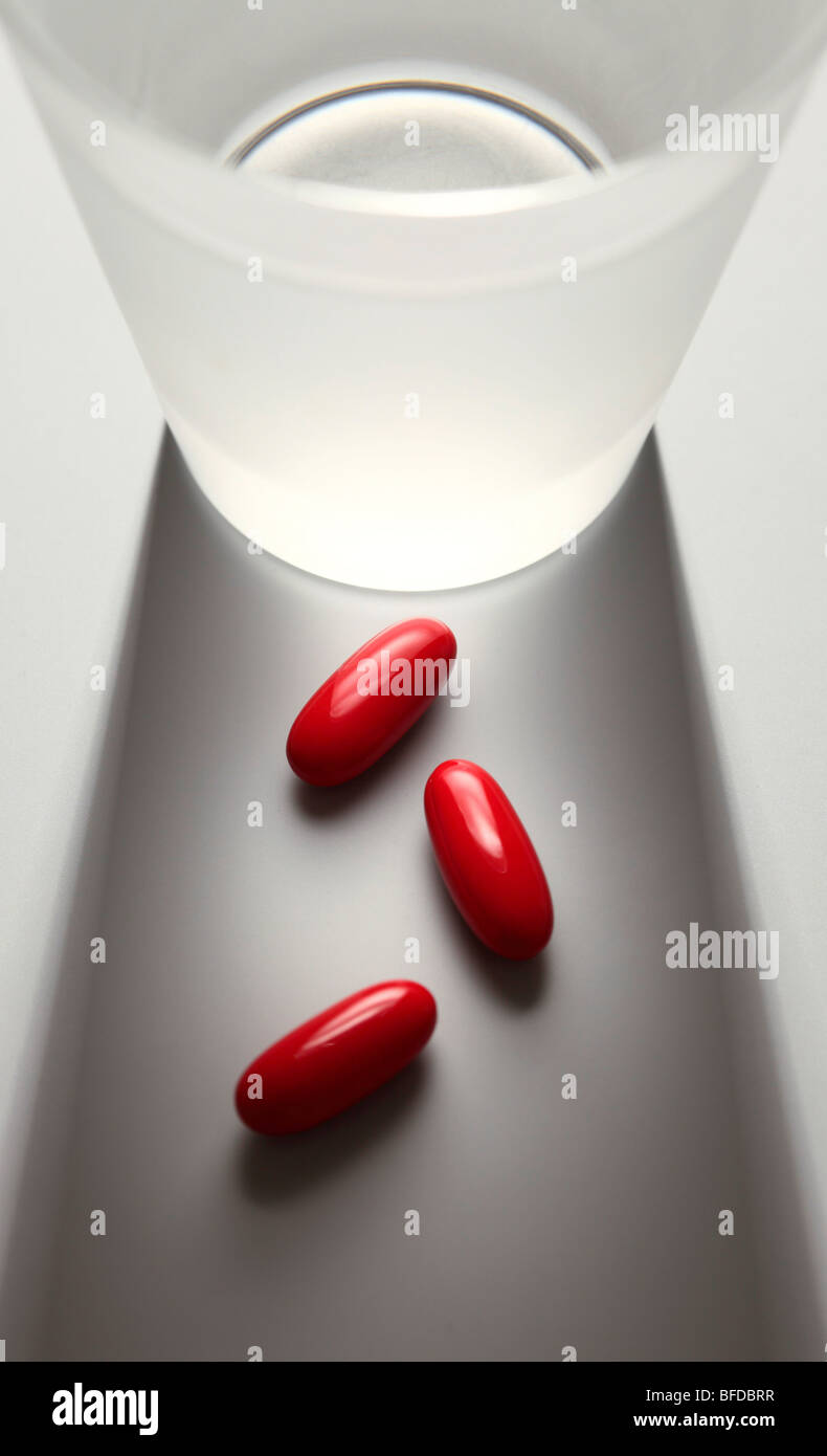 Tabletten neben einem Glas Wasser Stockfoto