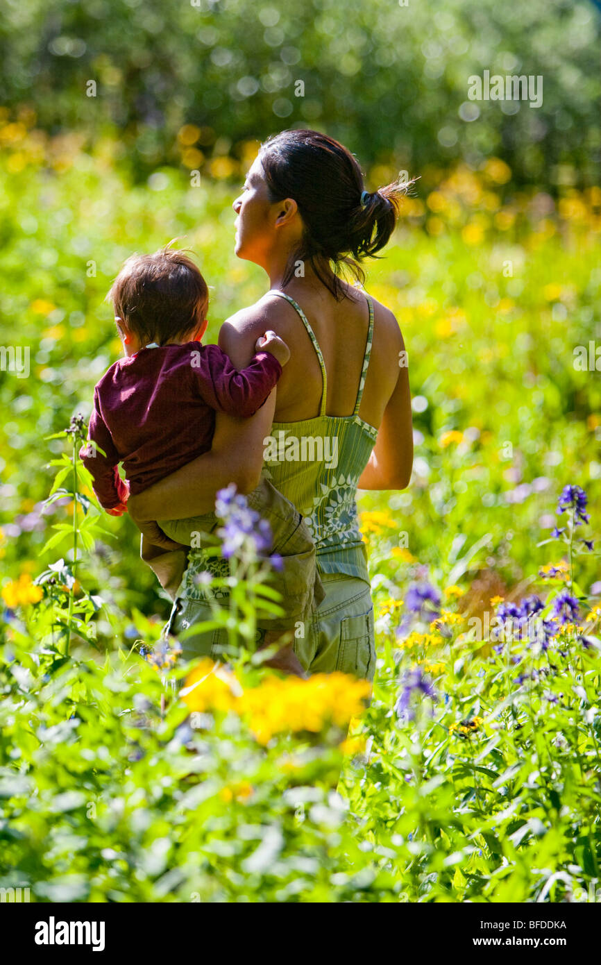 Mutter trägt 14 Monate alten Sohn in Wiese von Wildblumen in die Maroon Bells in Snowmass Wildnis außerhalb von Aspen, Colorado Stockfoto