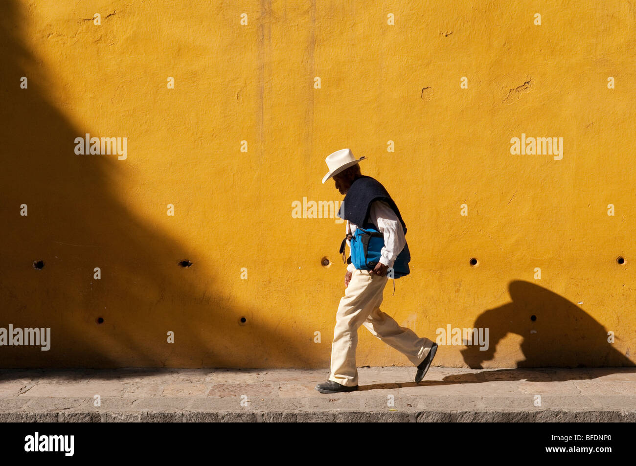 Mann zu Fuß vor der gelben Wand; San Miguel de Allende, Mexiko. Stockfoto