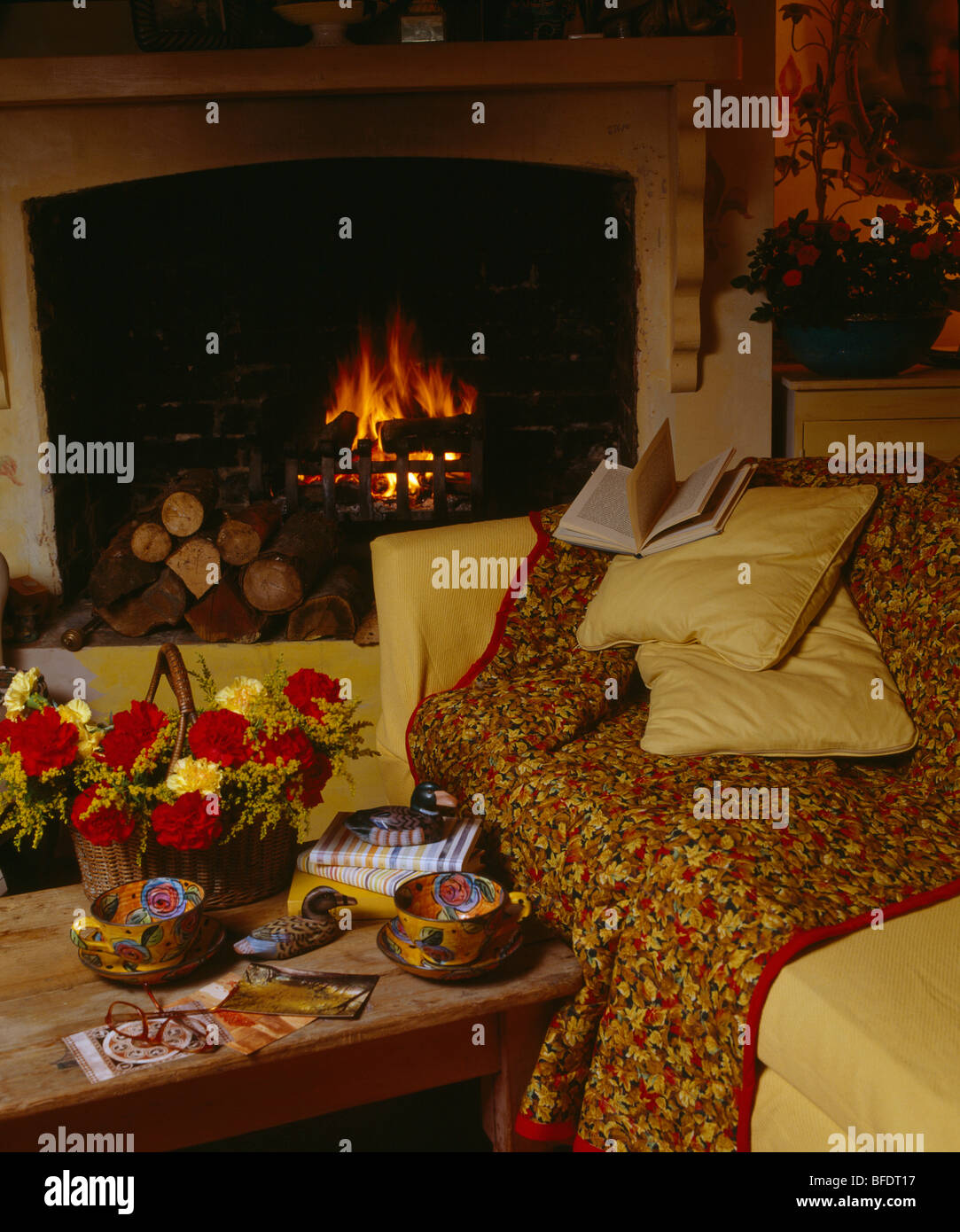 Gesteppte Wurf auf gelben Sofa vor dem Kamin im gemütlichen Wohnzimmer Stockfoto