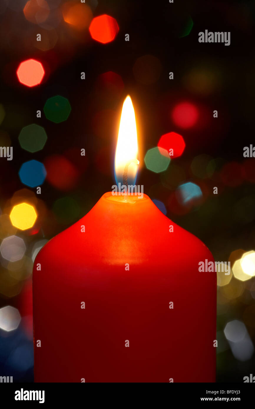 rot Weihnachtskerze brennt vor einem Weihnachtsbaum Stockfoto