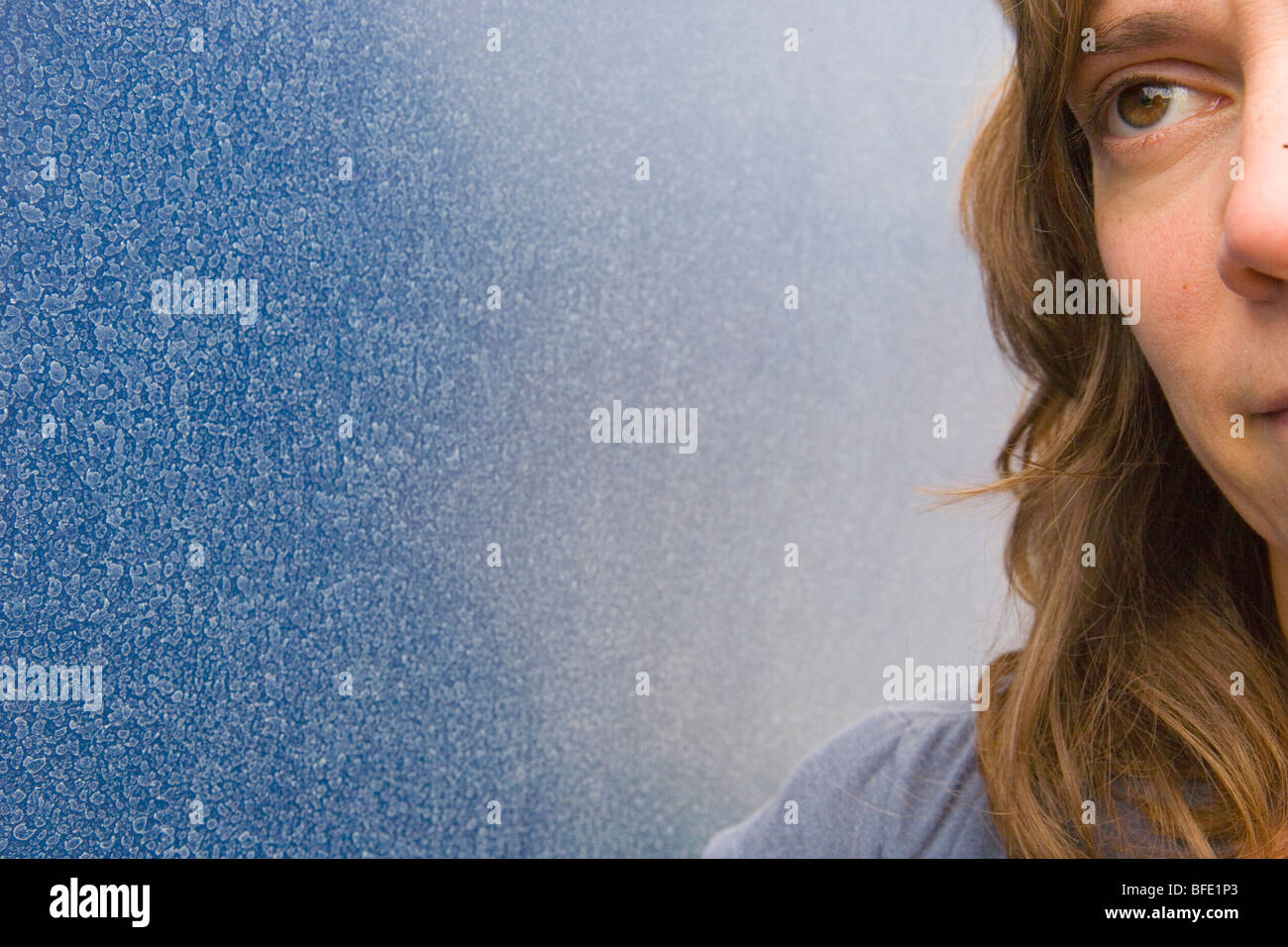 Nahaufnahme einer Frau hellwach vor einer blauen Wand Stockfoto