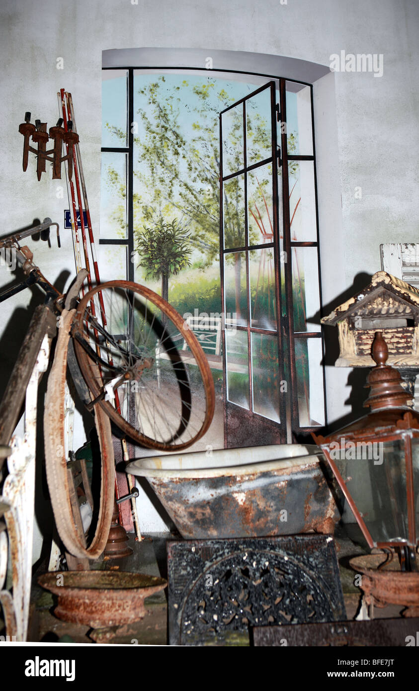 Array von Elementen auf einer indoor Antiquitätenmarkt vor einer dynamischen Wandbild Fenstertüren öffnen auf Terrasse und Gärten Stockfoto