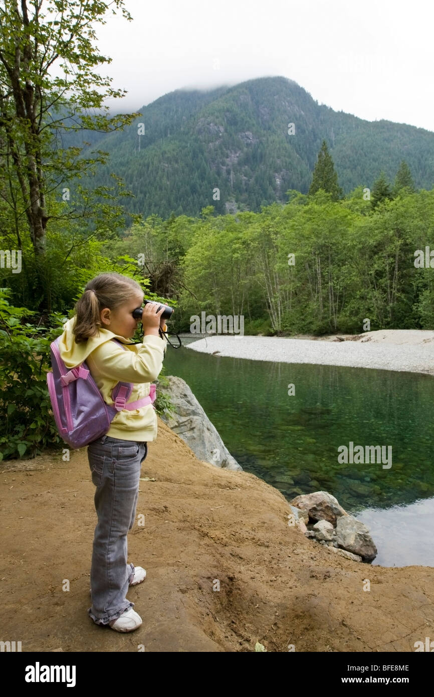 Kleines Mädchen auf der Suche durch ein Fernglas auf einem Wanderweg am Golden Ears Provincial Park in Maple Ridge, British Columbia, Kanada Stockfoto