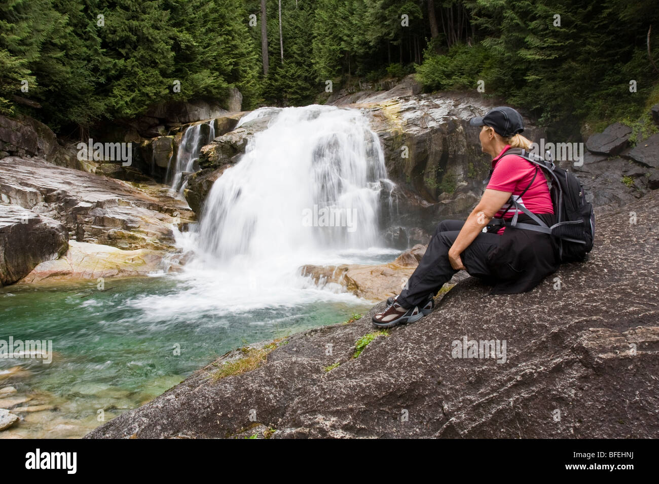 Frau Wanderer sitzen auf Felsen Blick auf Wasserfälle in Golden Ears Provincial Park in Maple Ridge, British Columbia, Kanada Stockfoto