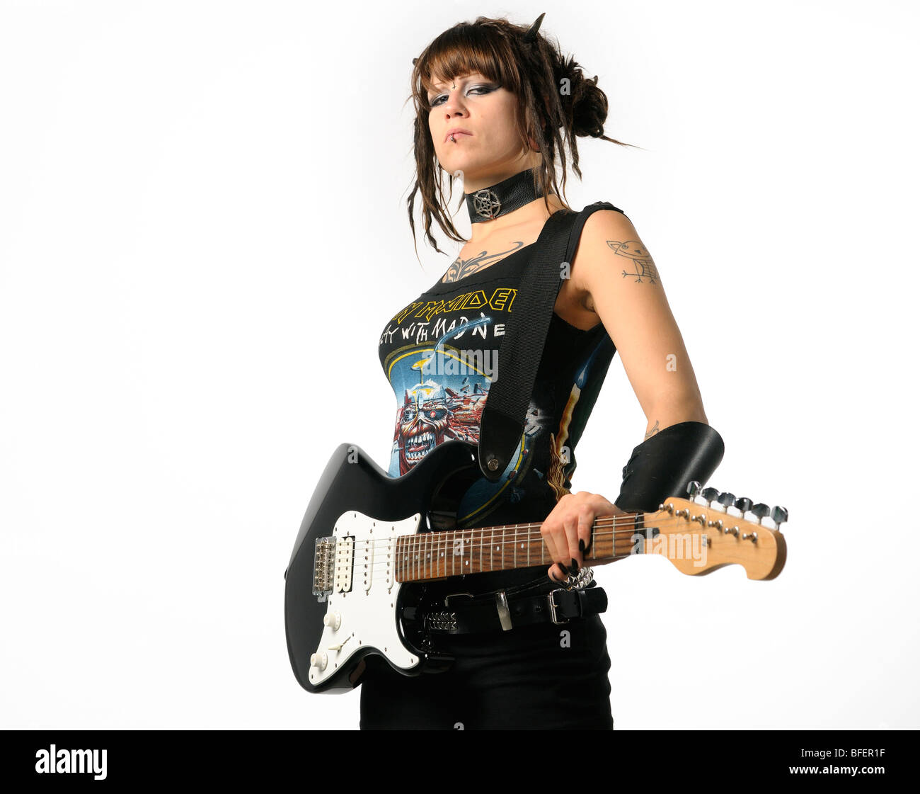 Heavy Metal chick mit Hörnern und Tätowierungen Holding eine schwarze Gitarre auf einem weißen Hintergrund Stockfoto