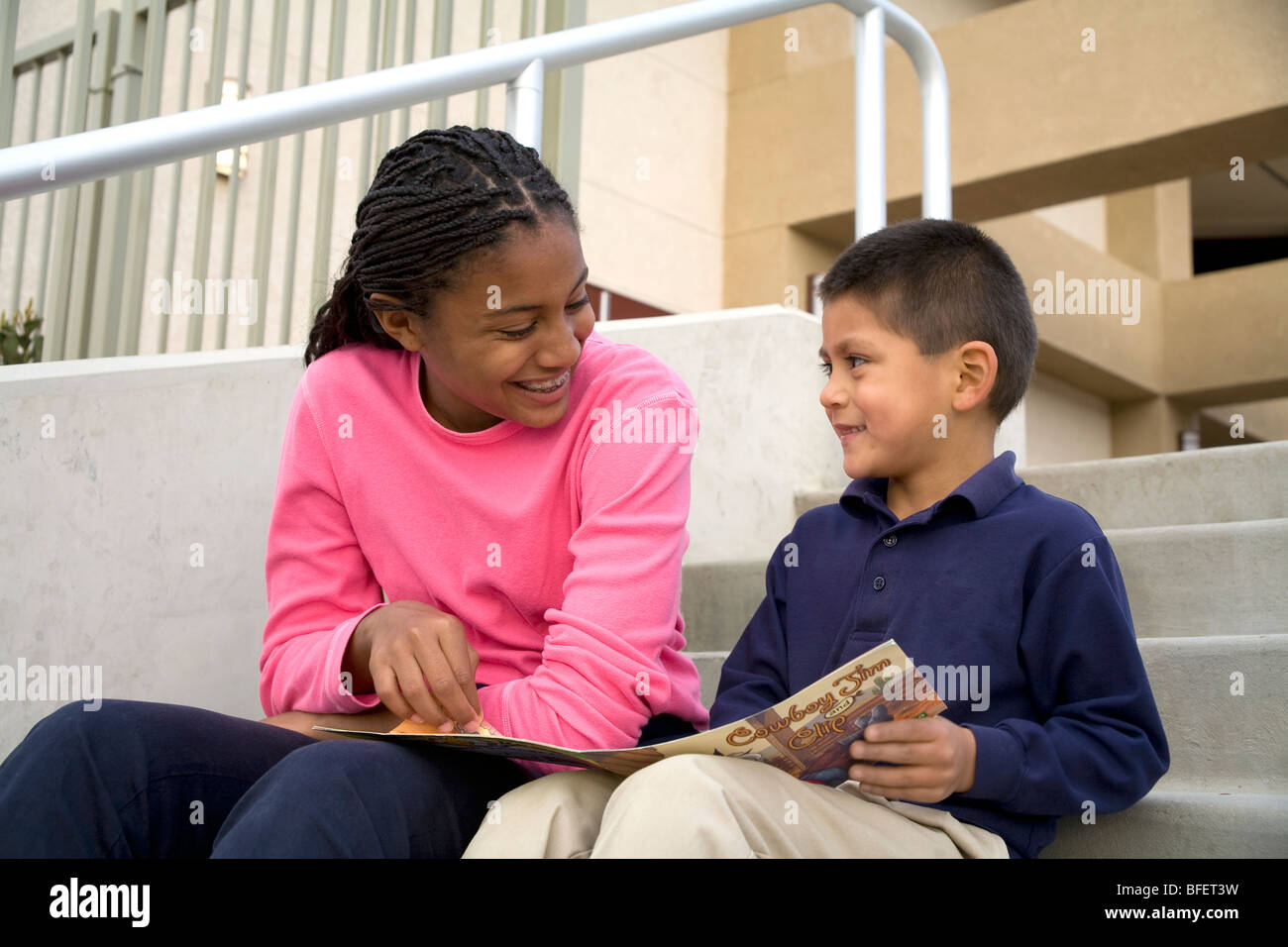 Ältere Teenager-Mädchen liest ein Buch spricht Lächeln Lächeln Förderung ermutigt junge 5-6 Jahre alten USA Herr © Myrleen Pearson Stockfoto