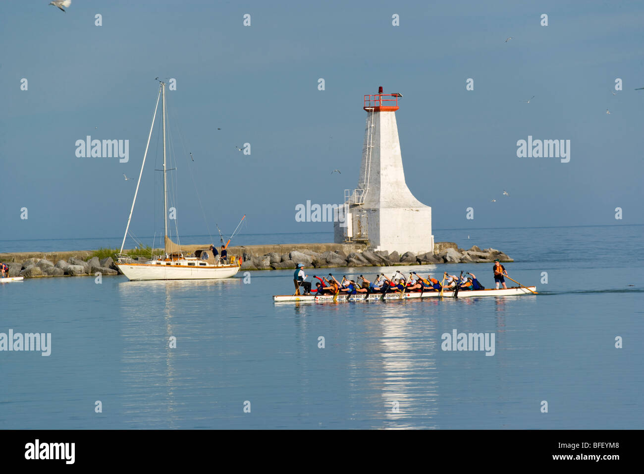 Segelboot, Drachenboot-Besatzung und Leuchtturm, Cobourg, Ontario, Kanada Stockfoto