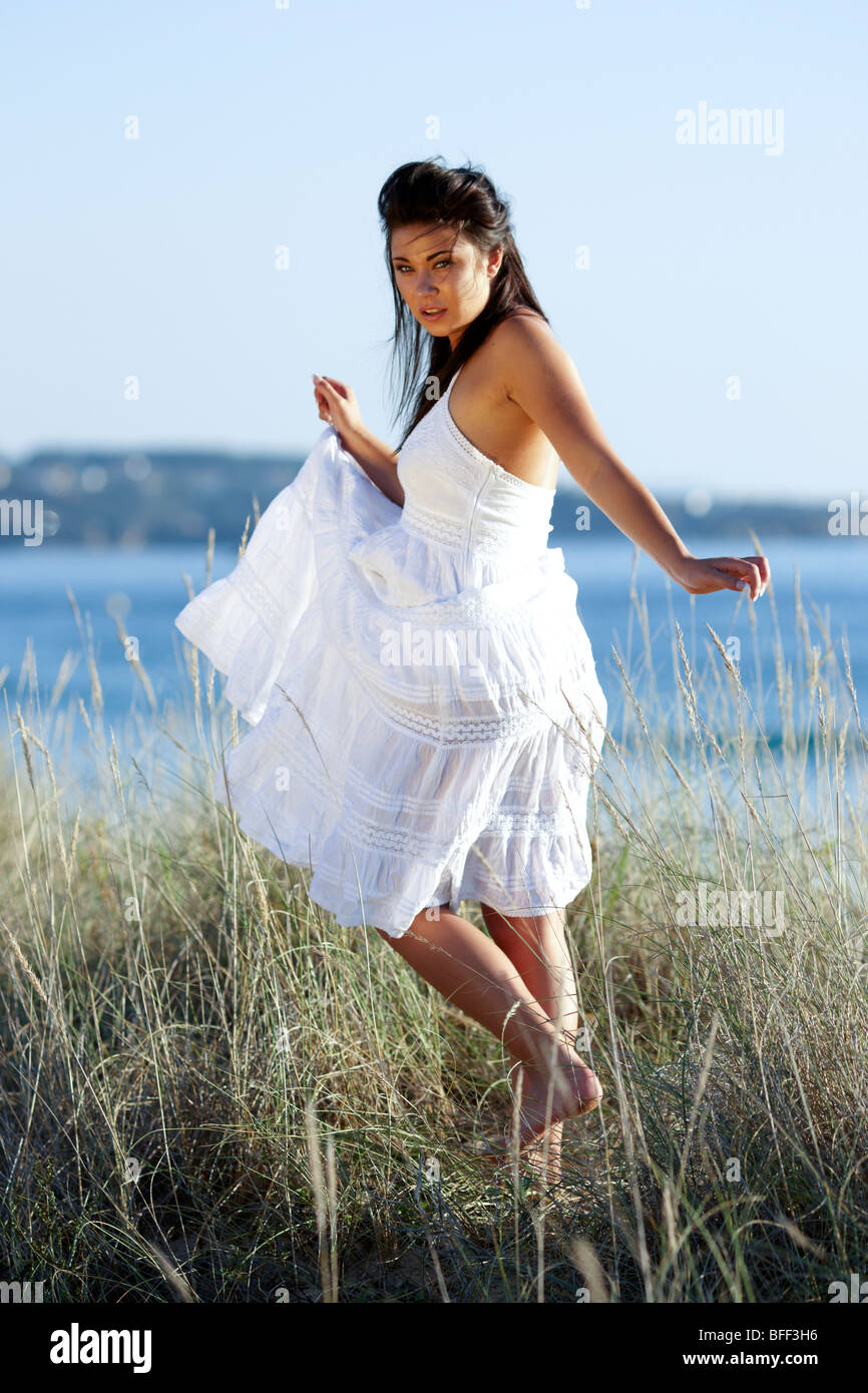 Mädchen zu Fuß im Dünengras weißen Kleid Stockfoto