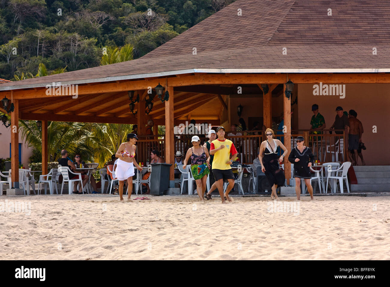 Resort-Tanzlehrer unterrichten Urlauber einen Latin-Stil Tanz vor einem Strand Seite Restaurant, sandigen Strand Stockfoto