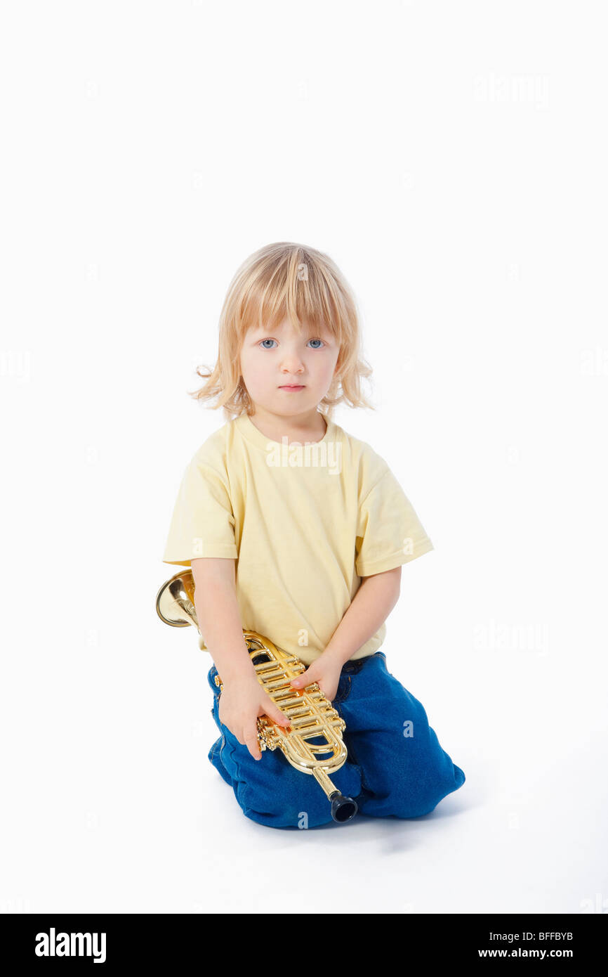 Junge mit langen blonden Haaren mit Spielzeug Trompete spielen Stockfoto