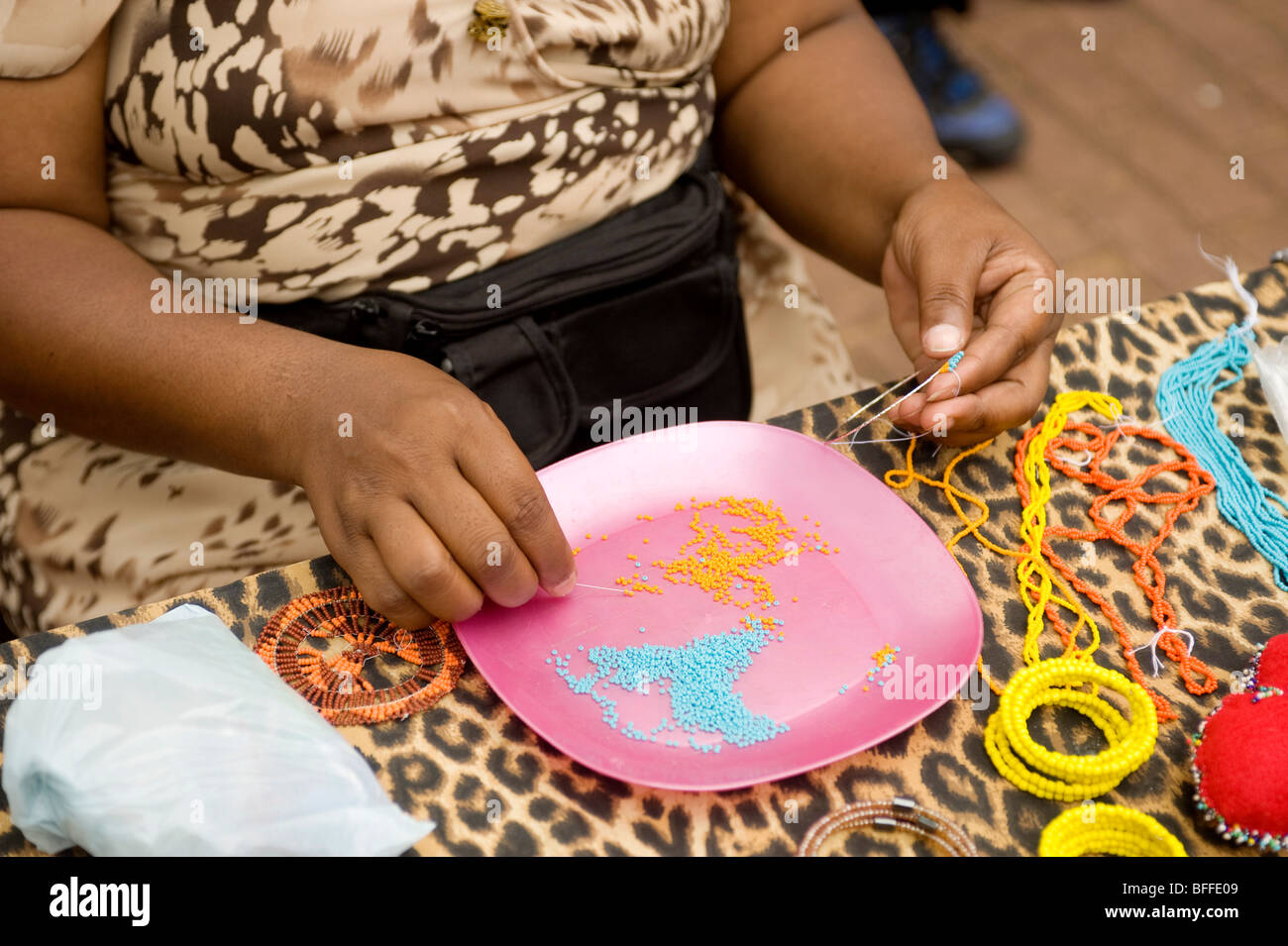 Frau Perle Hals Schnürsenkel zu machen. Ellis Park Street Market. Durban, Südafrika Stockfoto