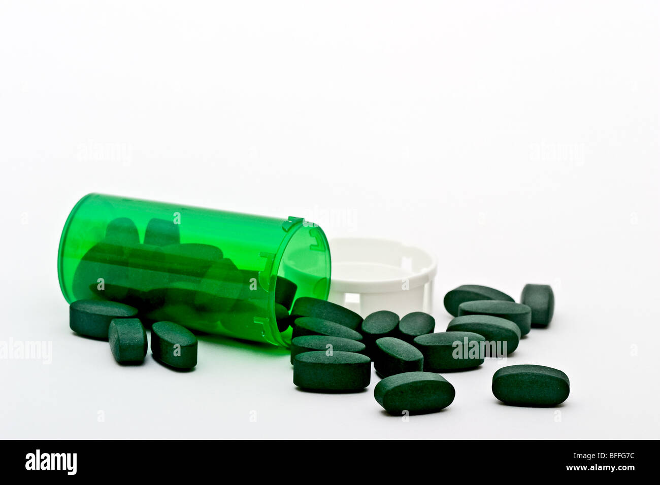 Grünes Rezept Flasche verschüttete mit grünen Pillen und einer Kunststoff-Kappe Stockfoto