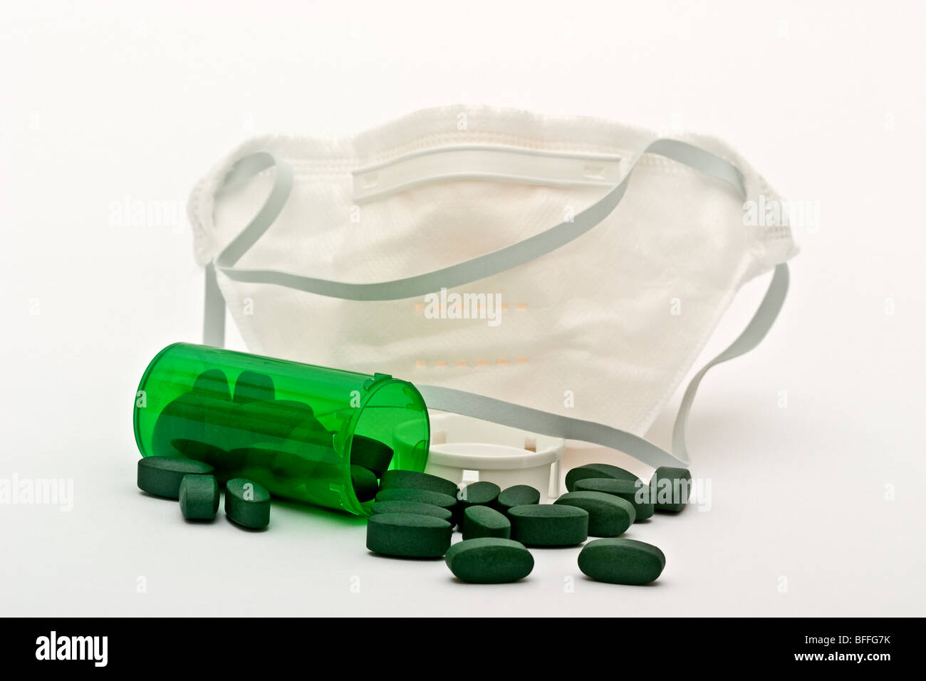 Grünes Rezept-Flasche mit grünen Pillen vor einer medizinischen Maske verschüttet Stockfoto