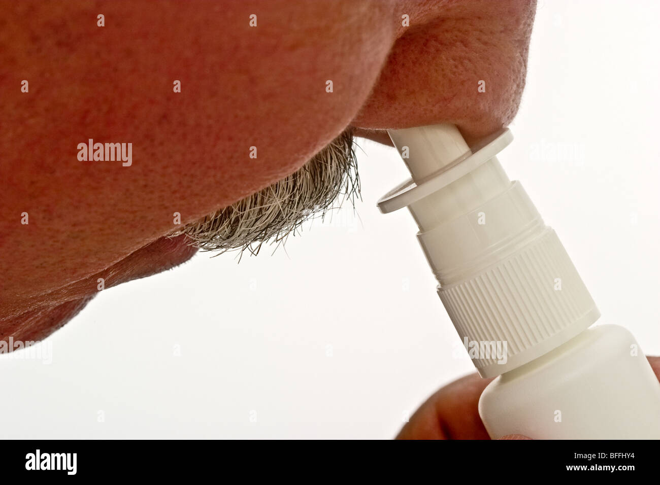 Mann mit Schnurrbart und einem Nasenspray Dispenser in seiner Nase Stockfoto