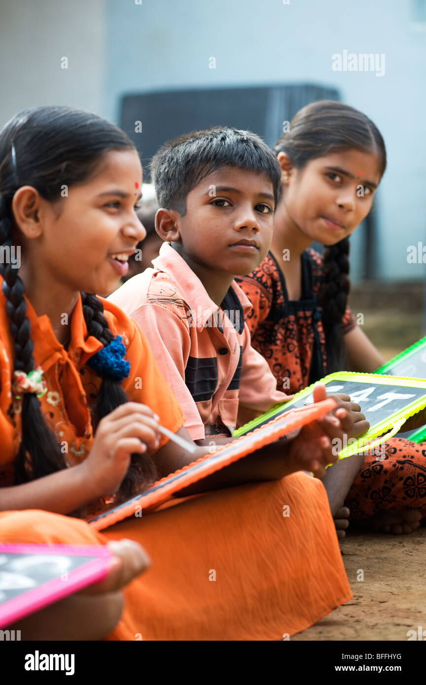 Indian School Kinder sitzen außerhalb ihrer Schule schreiben auf der Schiefertafel. Andhra Pradesh, Indien. Selektiver Fokus Stockfoto