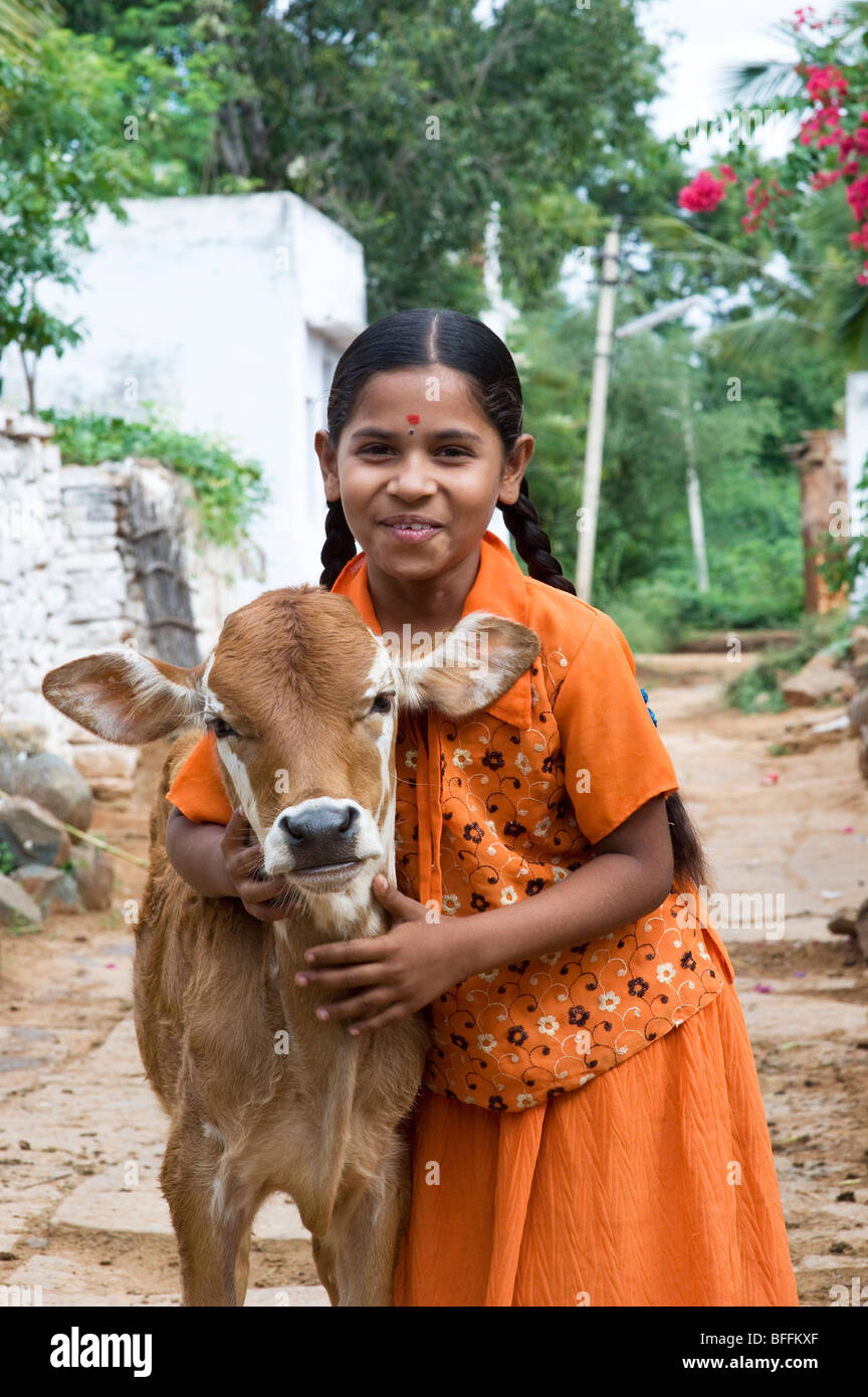 Junge indische Dorfmädchen umarmt eine Kalb in einem indischen Dorf. Andhra Pradesh, Indien Stockfoto