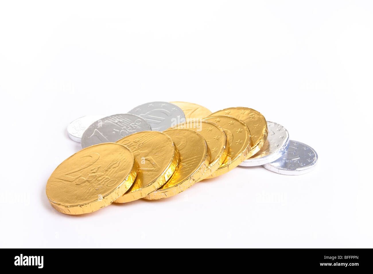Gold und Silber Folie verpackt Schokolade Euro vor weißem Hintergrund mit flachen Fokus. Stockfoto