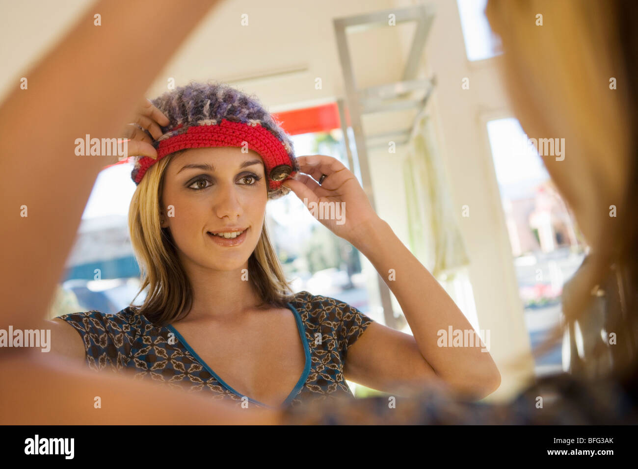 Junge Frau, die versucht auf Hut im shop Stockfoto