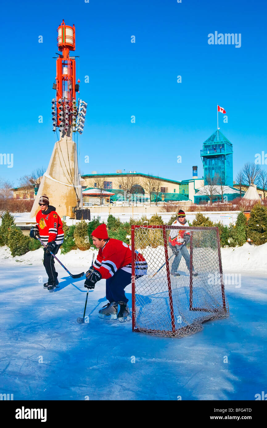 Junge Männer spielen Eishockey auf der Assiniboine River in The Forks im Zentrum von Winnipeg, Manitoba, Kanada. Stockfoto