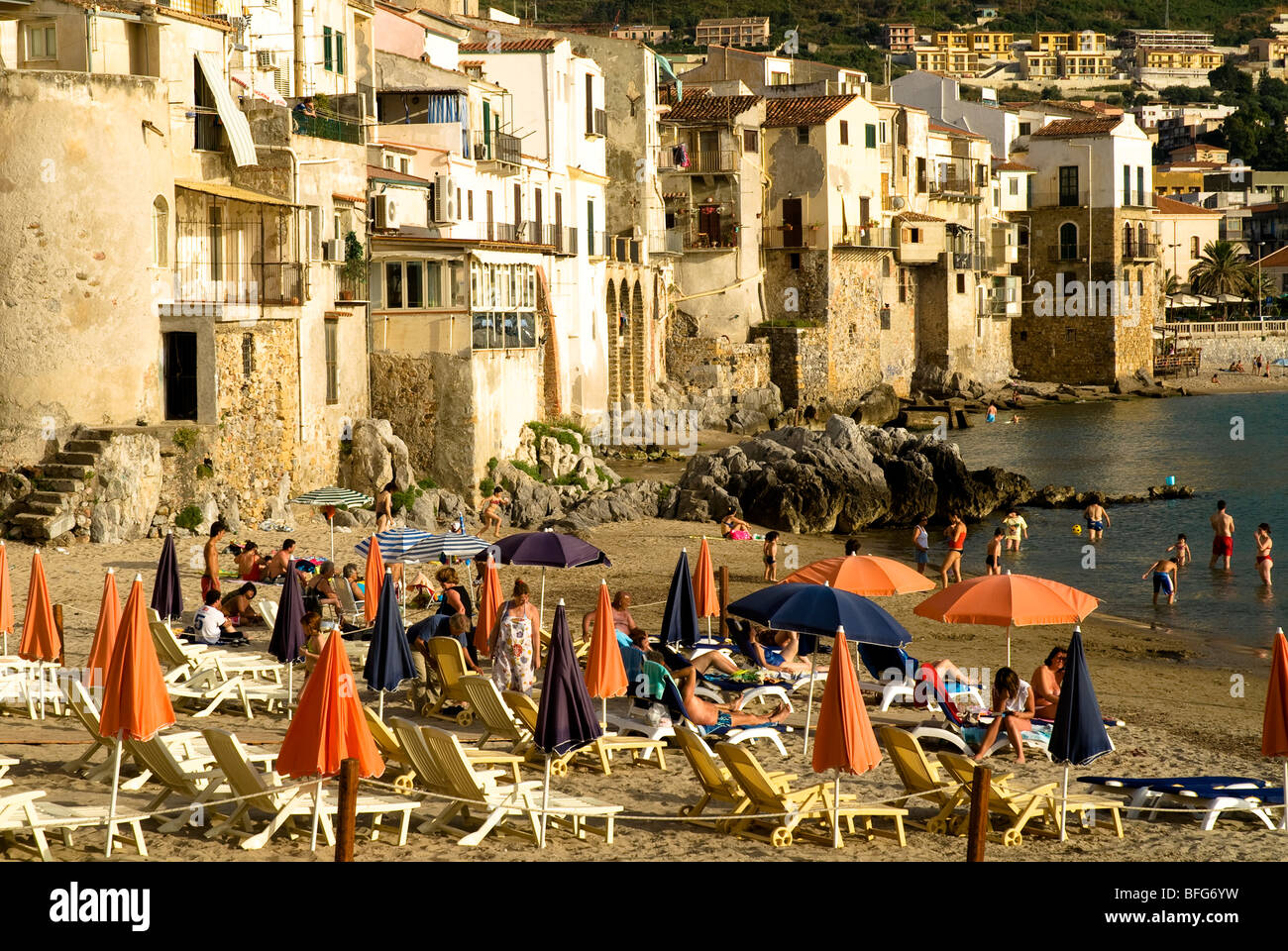 Sonne-Badegäste, Liegestühle und Sonnenschirme am Strand von Cefalu, Sizilien, Italien Stockfoto