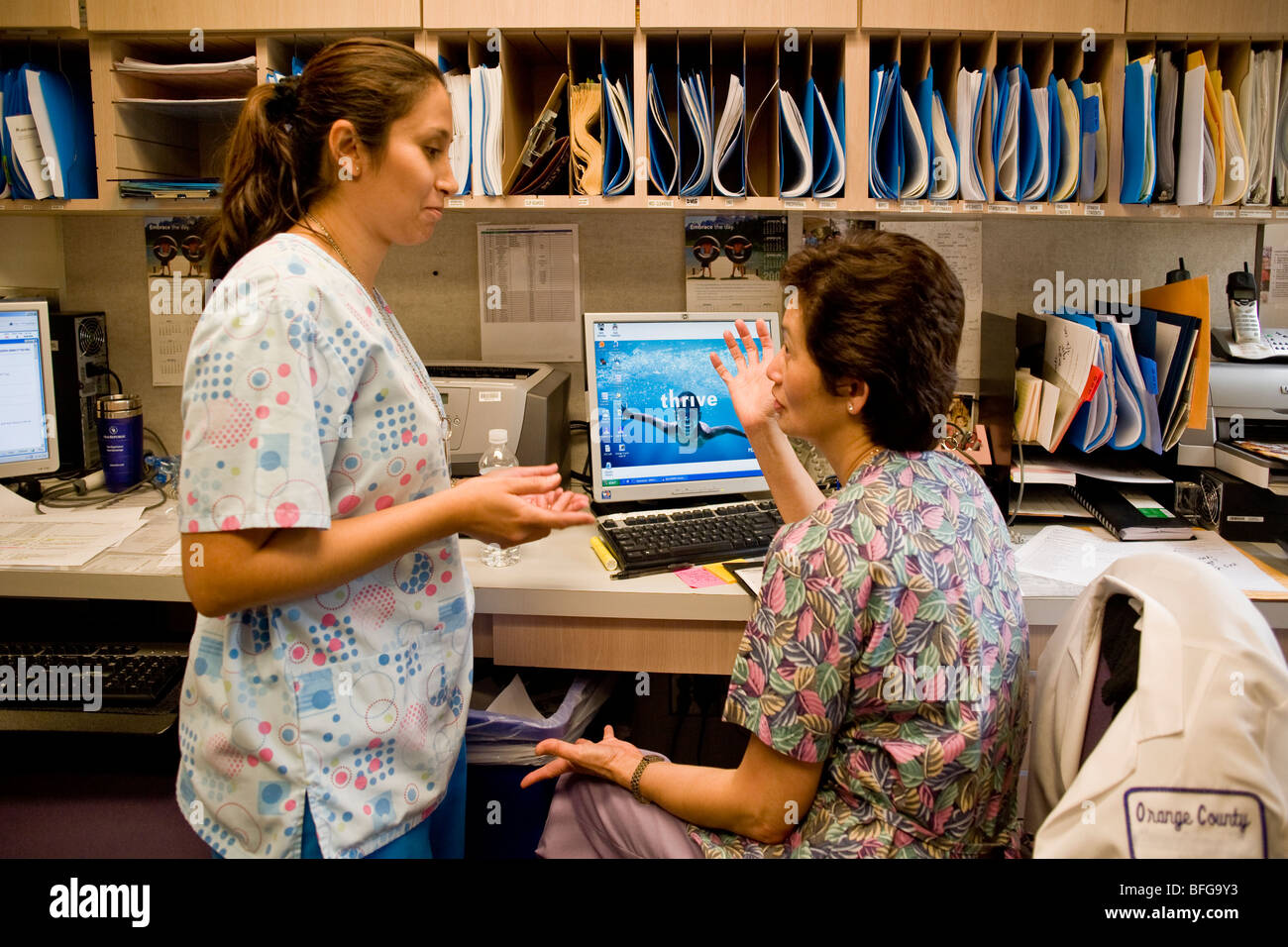 Lateinamerikanische und asiatische Fachkräfte des Gesundheitswesens unterhalten bei einer California Health Maintenance Organisation. Stockfoto
