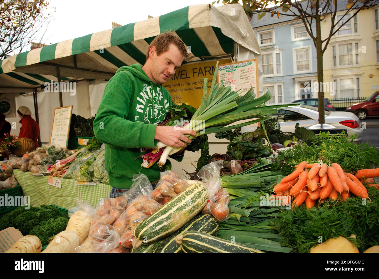 Junger Mann, Kauf oder Verkauf von frischem Gemüse auf Aberystwyth Farmers Market, Ceredigion, Wales UK Stockfoto