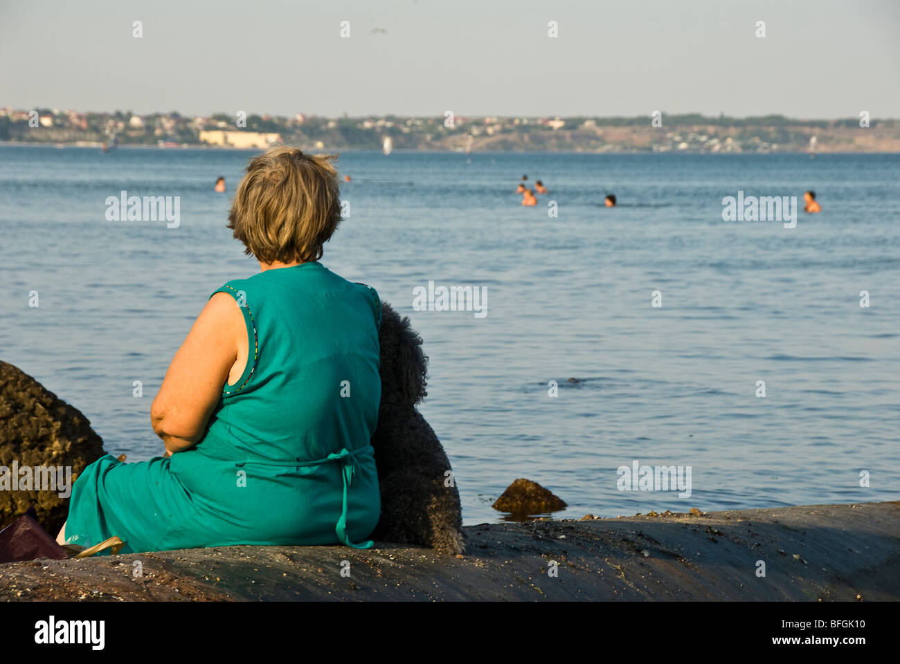 ältere Dame mit ein Hund sitzt in der Nähe des Meeres Stockfoto