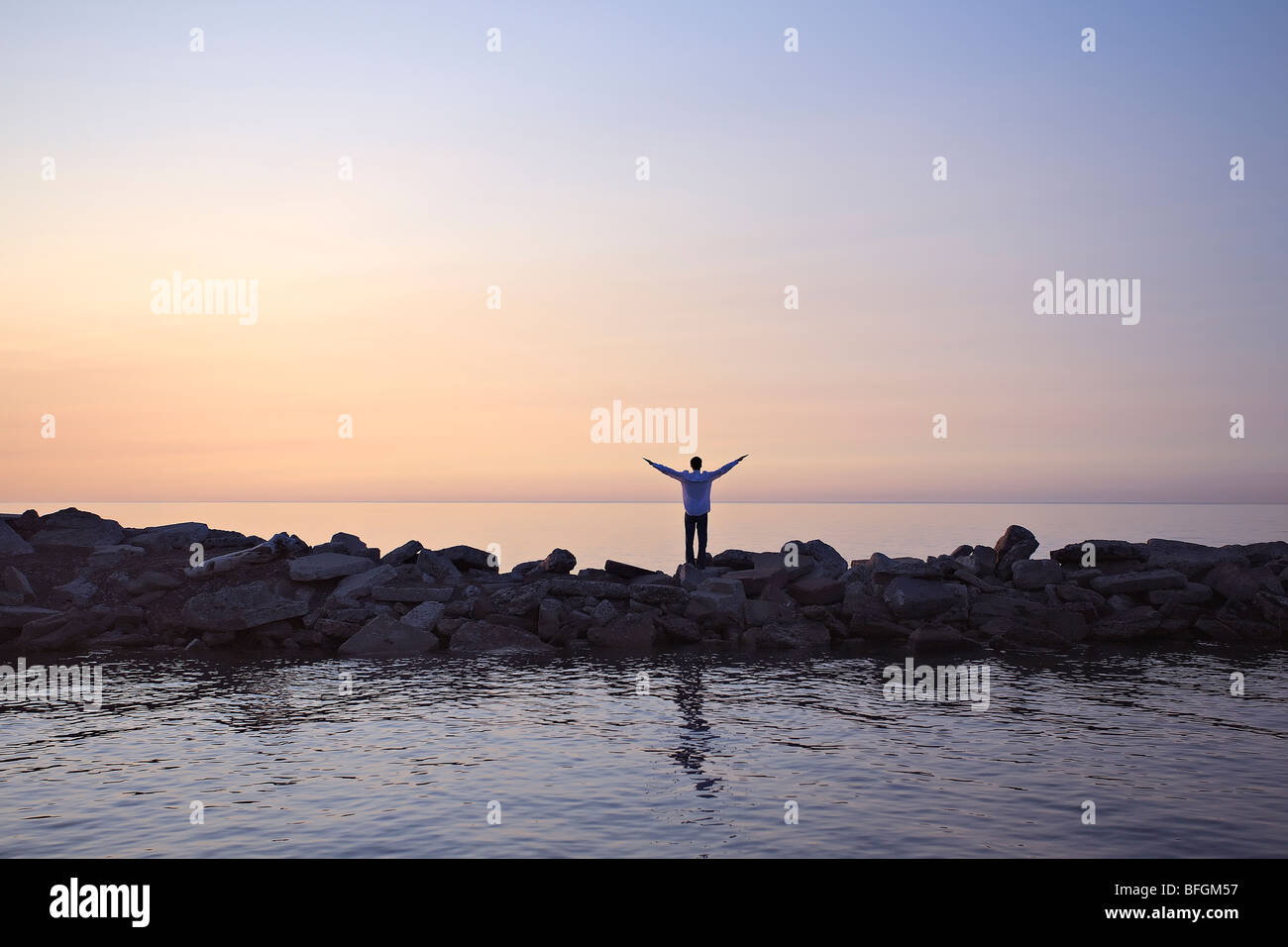 Mann steht auf Wellenbrecher bei Sonnenaufgang, Lake Ontario, Woodbine Strand, Toronto, Ontario Stockfoto