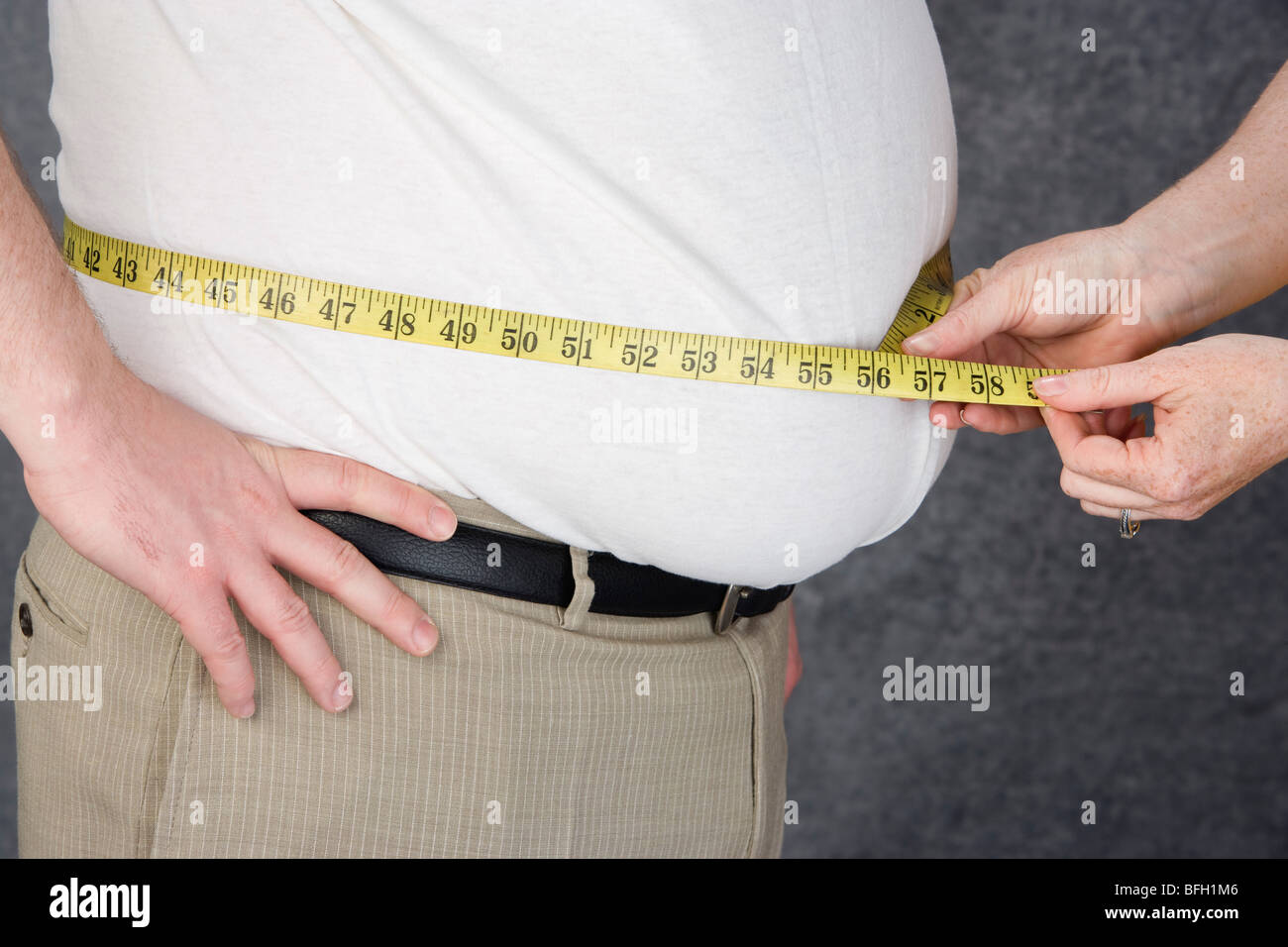 Frau messen Taille übergewichtiger Mann mit Maßband, Mittelteil Stockfoto