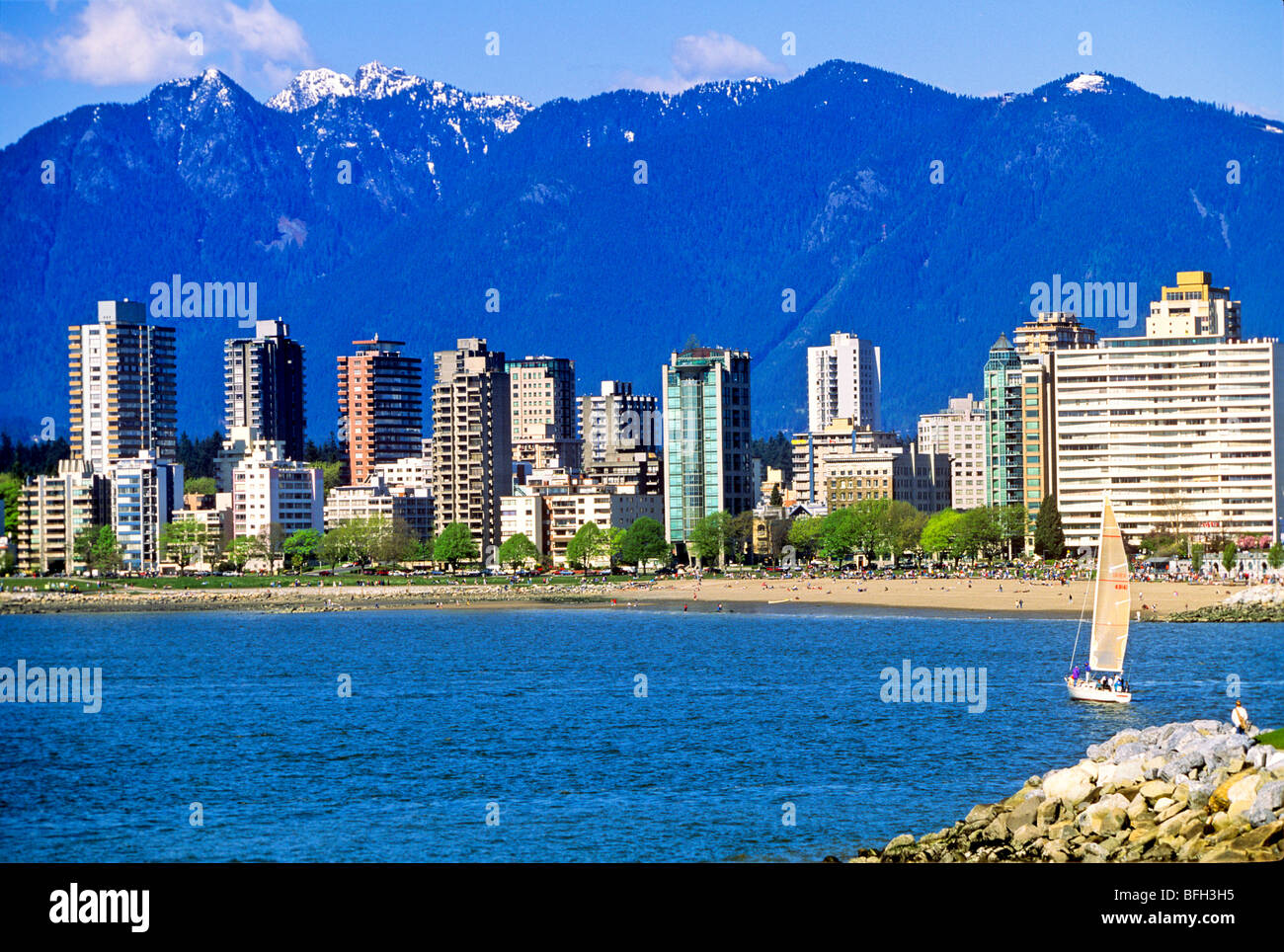 Segelboot in English Bay mit Eigentumswohnungen und Bergen im Hintergrund, Vancouver, Britisch-Kolumbien, Kanada Stockfoto