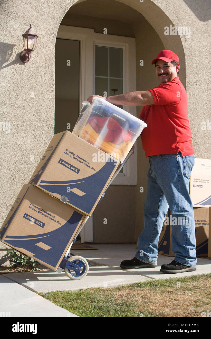 Lieferung Mann Betrieb Wagen mit Stapel von Containern Stockfoto