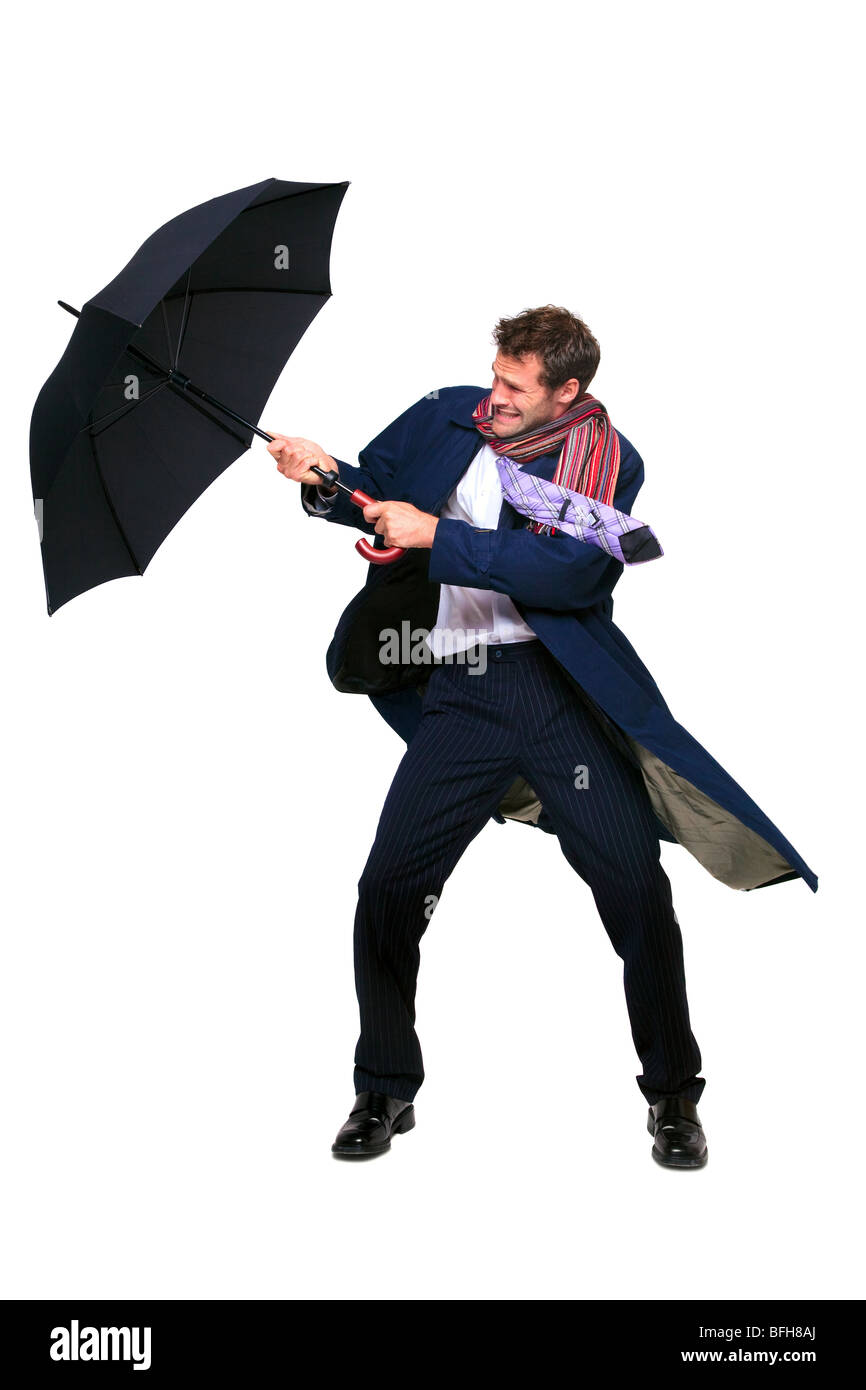 Studioaufnahme eines Geschäftsmannes, kämpfen mit einem Regenschirm in den Wind, isoliert auf einem weißen Hintergrund. Stockfoto