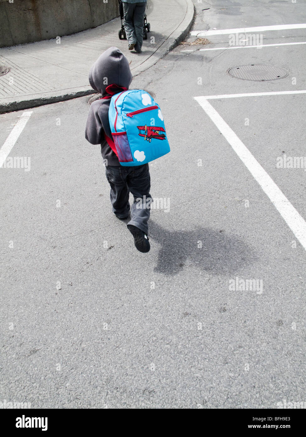 3,5 Jahre alten eurasischen junge mit einem Rucksack die Straße überqueren Stockfoto