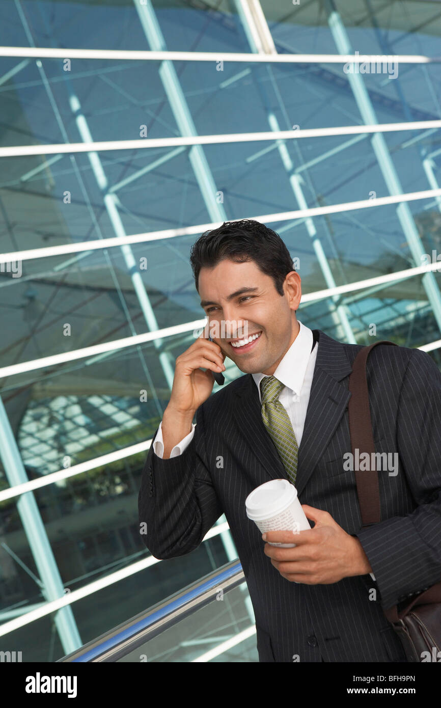 Geschäftsmann mit Mobiltelefon mit Take away Kaffee vor Bürogebäude Stockfoto