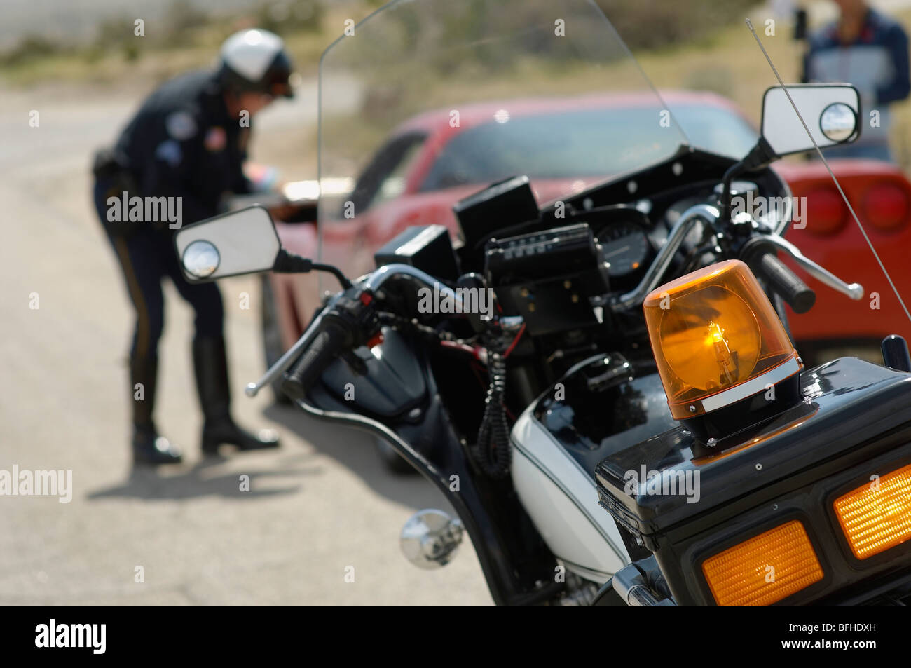 Verkehrspolizist im Gespräch mit Pkw-Fahrer, Schwerpunkt Motorrad im Vordergrund Stockfoto