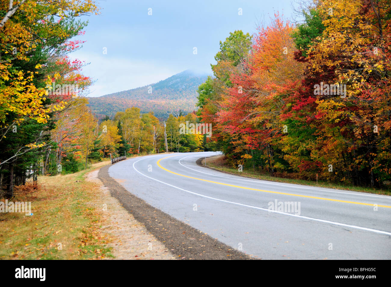 Eine Straße schlängelt sich durch den nebligen, gesättigt Herbst Farbe in den White Mountains, New Hampshire, USA. Stockfoto