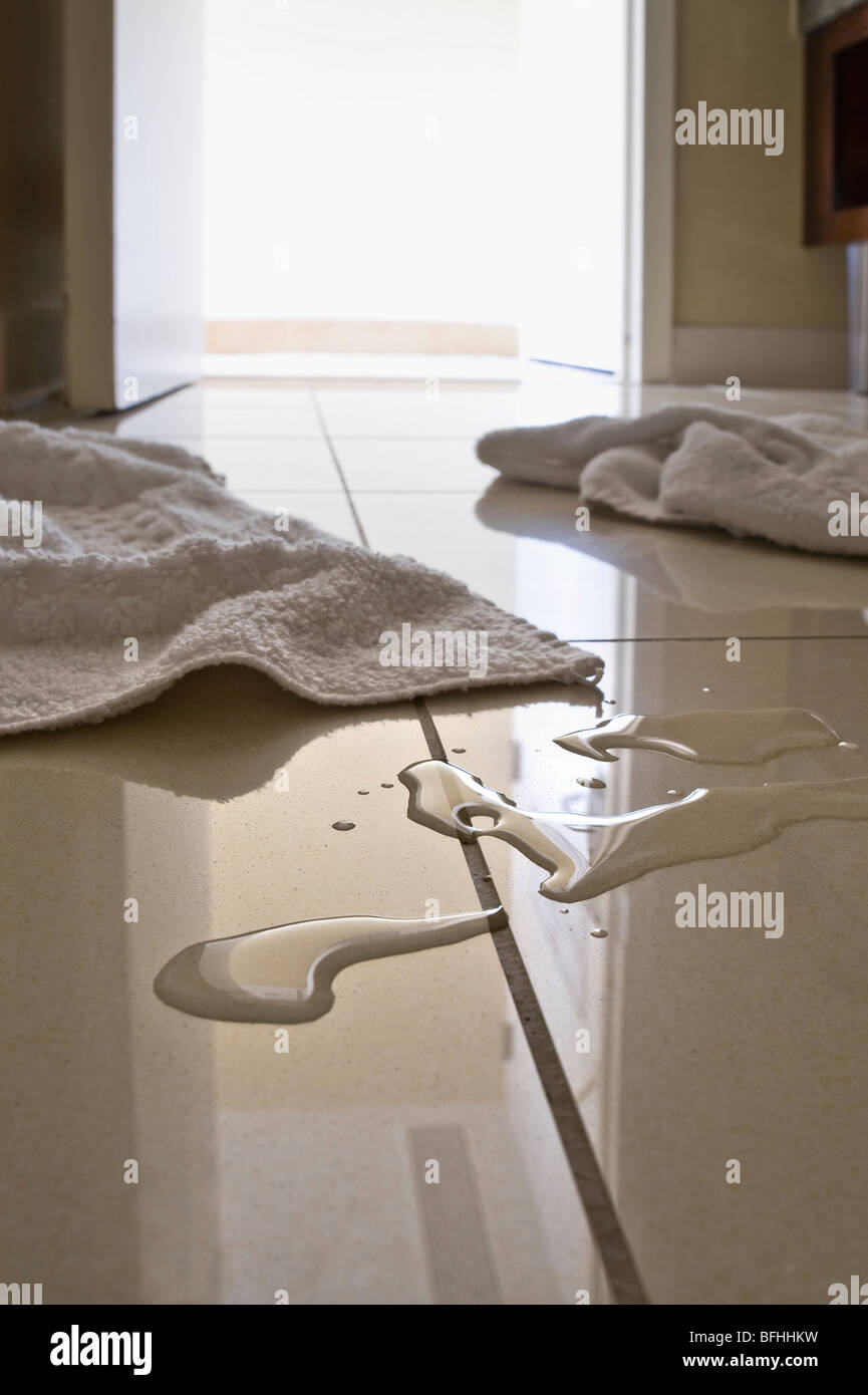Wasserpfützen & Handtücher auf Badezimmerboden Stockfoto
