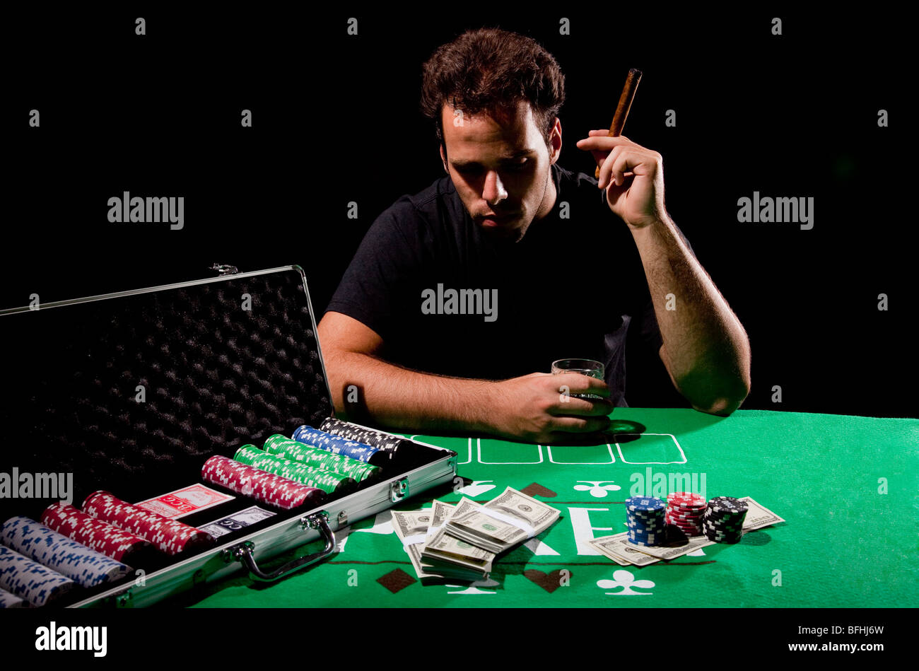 Eine junge männliche Spieler am Spieltisch hält eine Zigarre-Model-Release verfügbar Stockfoto