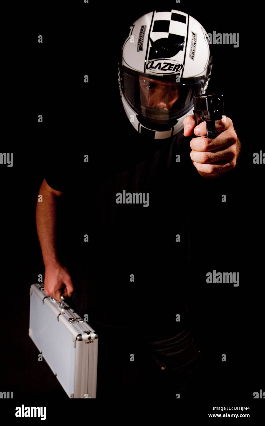 Mann mit Helm und Geld Motorradtasche hält Handfeuerwaffe im Viewer - Modell Rellease zur Verfügung Stockfoto