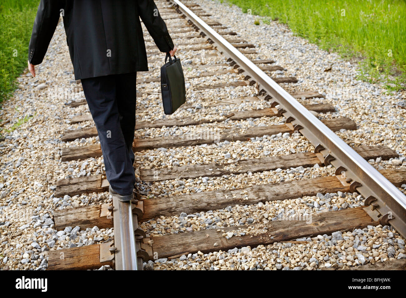 Mittleres Alter Geschäftsmann zu Fuß auf Schiene-Straße-Linie mit dem Aktenkoffer in der hand. Stockfoto