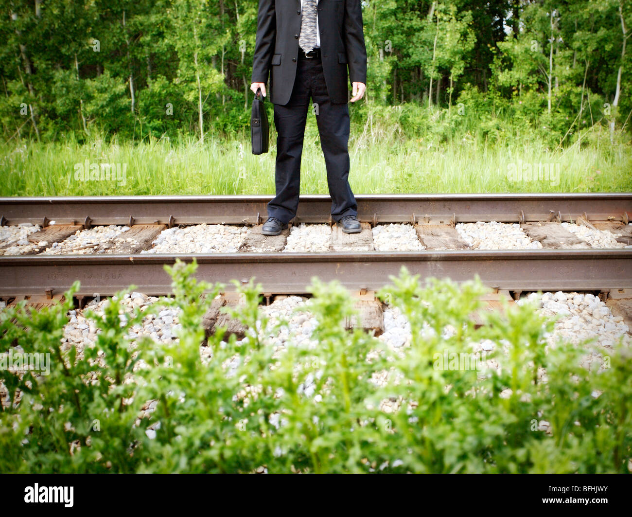 Mittleres Alter Geschäftsmann zu Fuß auf Schiene-Straße-Linie mit dem Aktenkoffer in der hand. Stockfoto