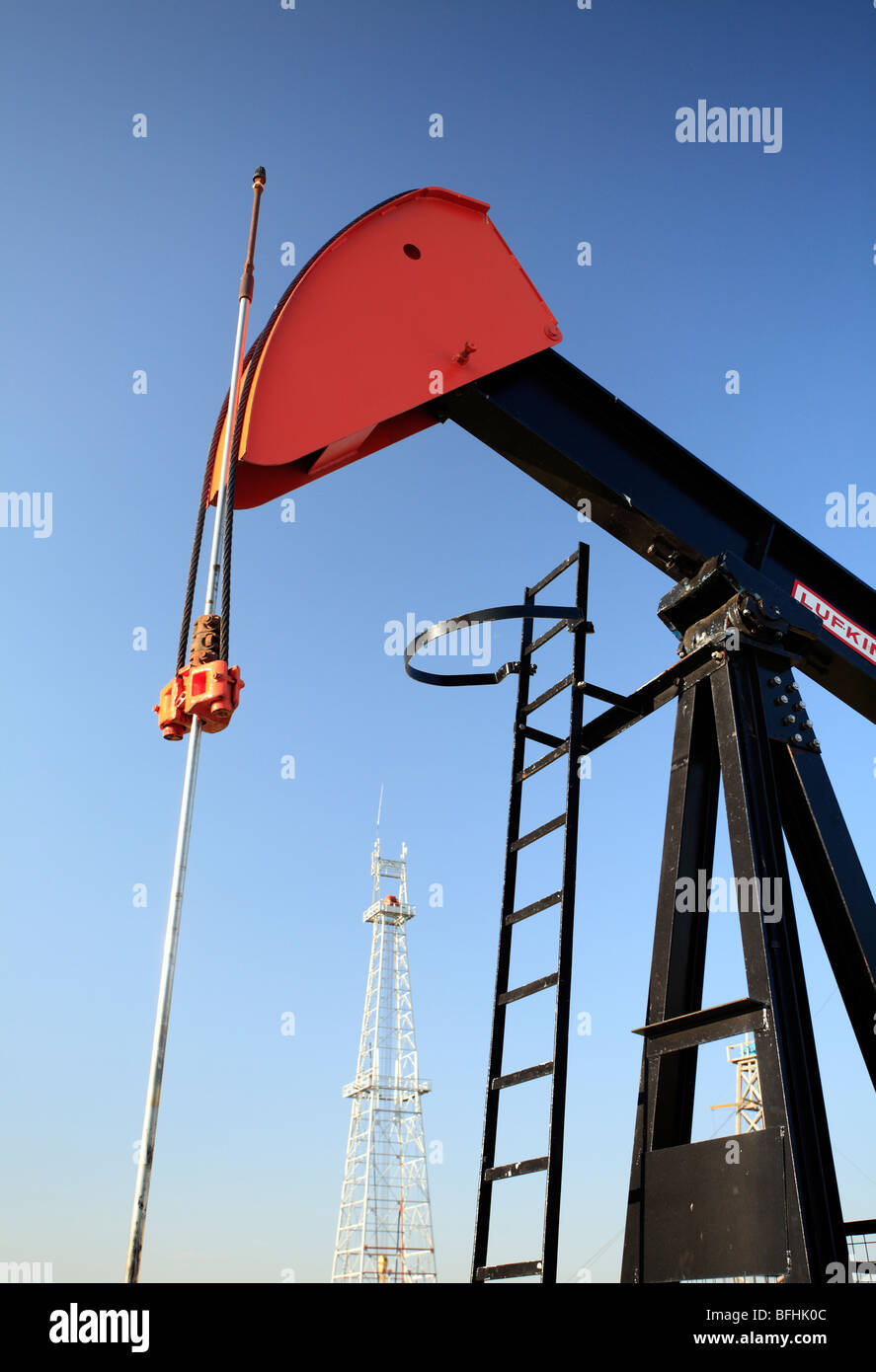 Pumpen Sie Jack mit Öl-Bohrinsel im Hintergrund Canadian Petroleum Discover Museum in Devon, Alberta, Kanada. Stockfoto