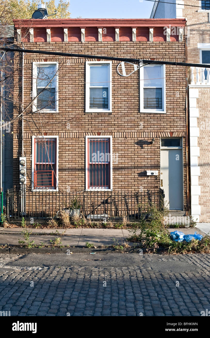 altes Haus mit ungewöhnlicher gemusterten Backsteinfassade & geschnitzt Holz Gesims auf gepflasterte Straße in Red Hook Brooklyn NY Stockfoto