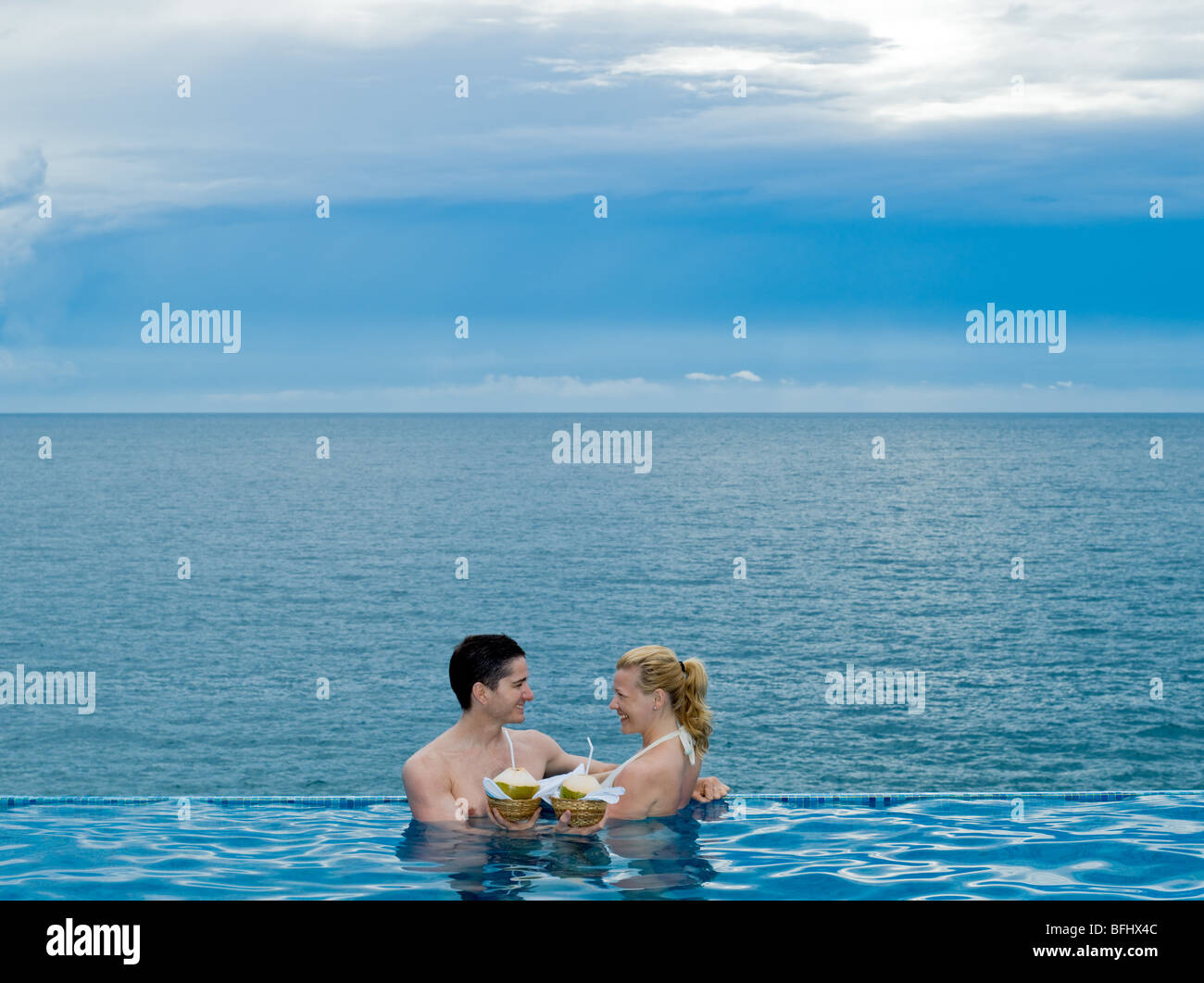 schöne Kaukasischen Paare genießen ihren Urlaub in einem Schwimmbad am Meer Kokosmilch trinken Stockfoto