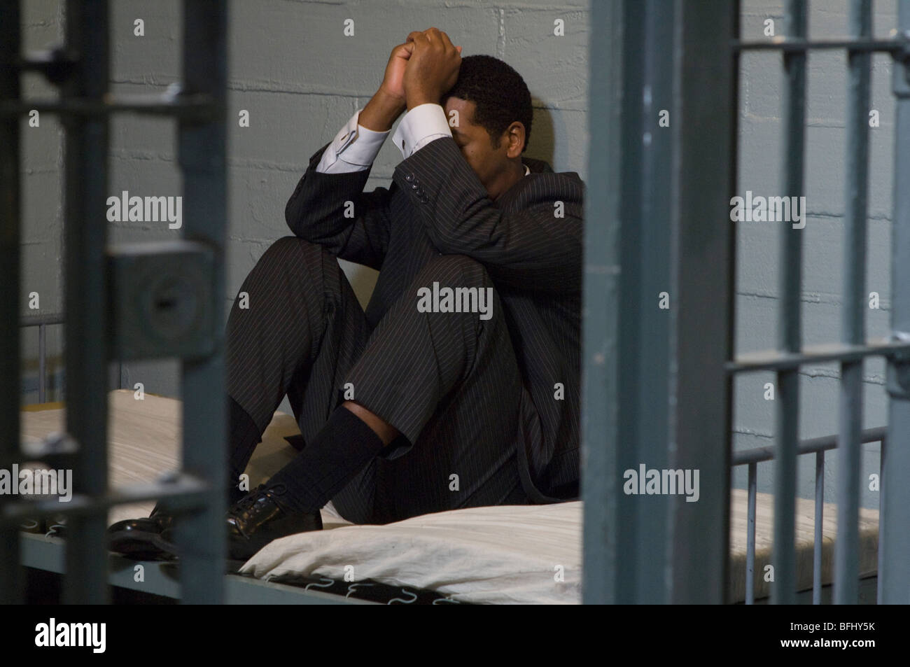 Geschäftsmann, sitzen auf Bett in Gefängniszelle Stockfoto