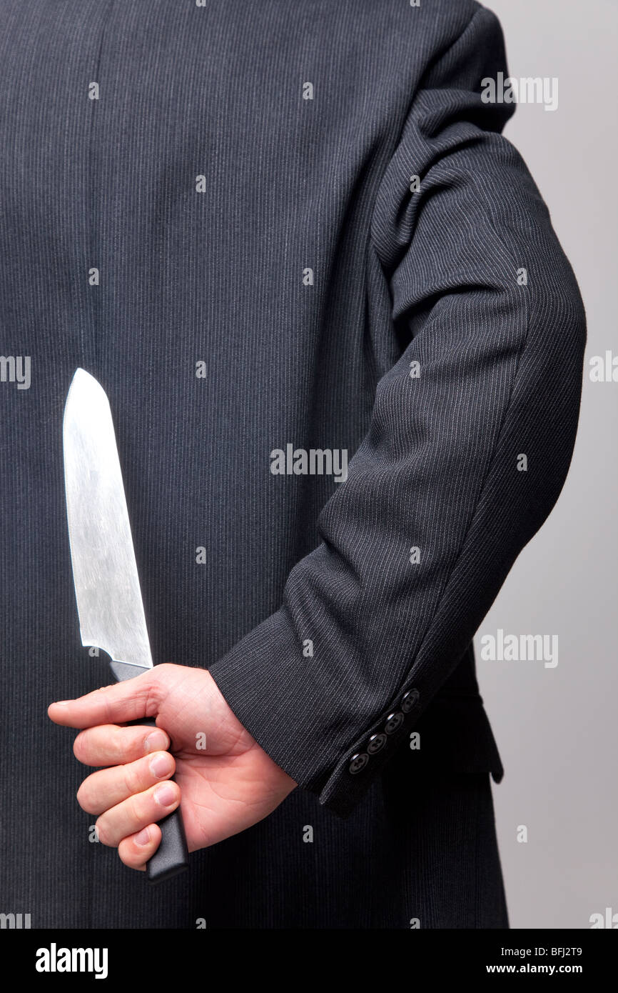 Nahaufnahme eines Unternehmers mit einem Messer hinter seinem Rücken. Stockfoto